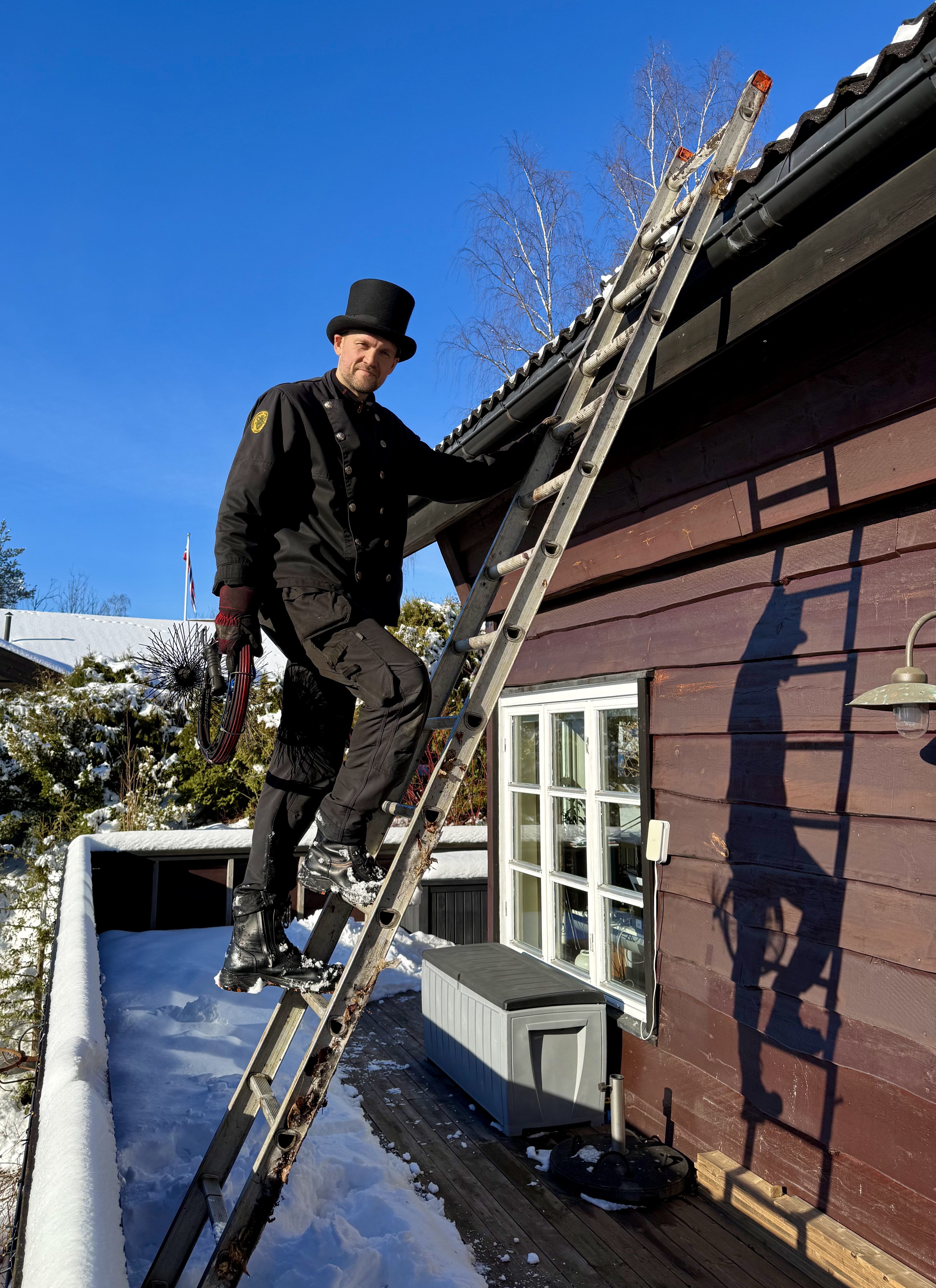 Feier klatrer opp stige til tak for å utføre feiing og tilsyn